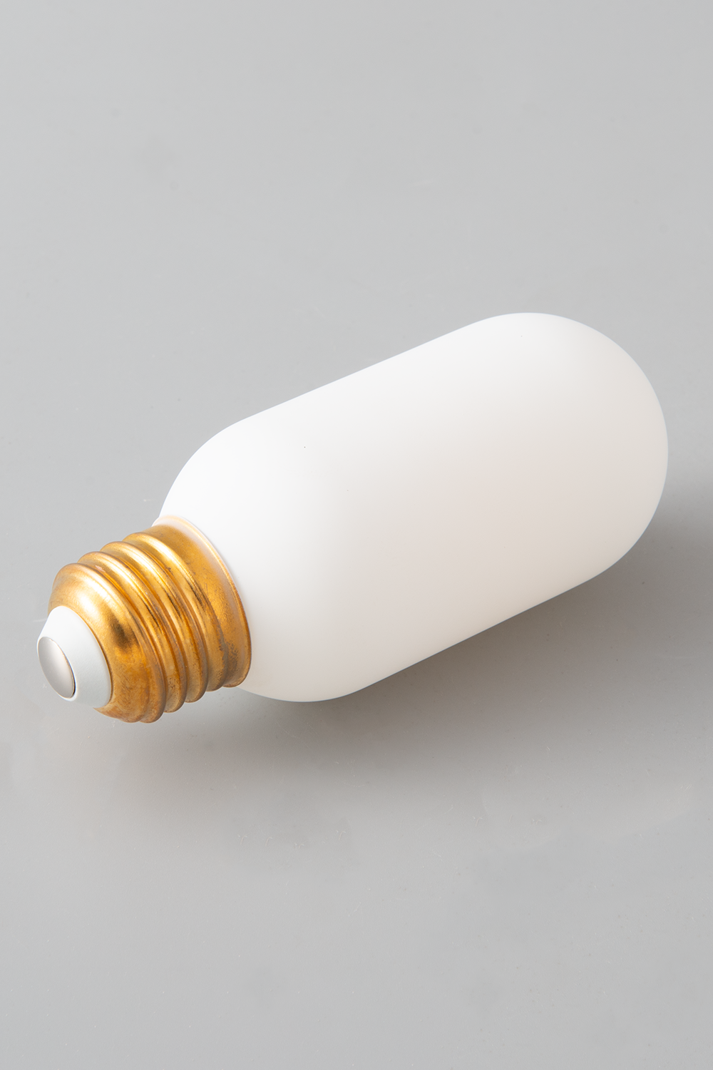 White T14 Brighlight LED bulb with brass base on a gray background