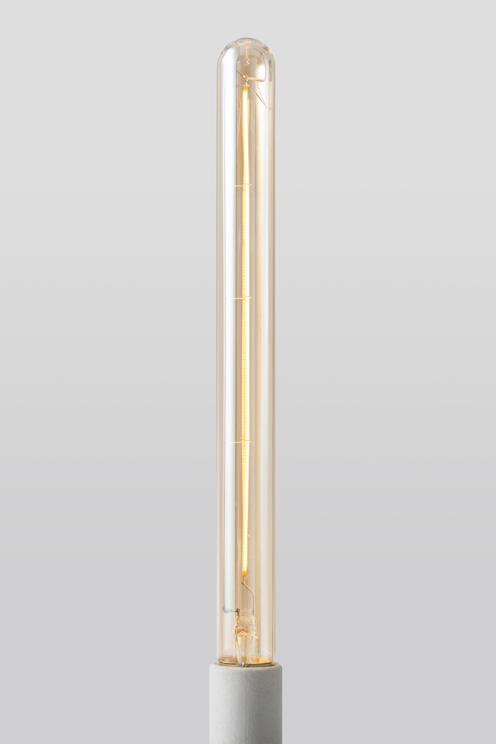 Close-up of Goldenline T8 LED bulb featuring warm amber glass and vintage-style filament for RH Edison Grand Sconce on a light grey background