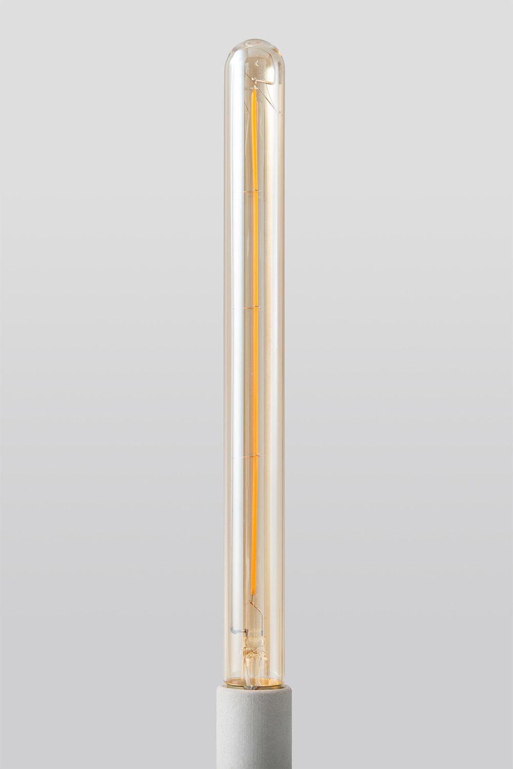 Close-up of Goldenline T8 LED bulb featuring warm amber glass and vintage-style filament for RH Edison Grand Sconce on a light grey background