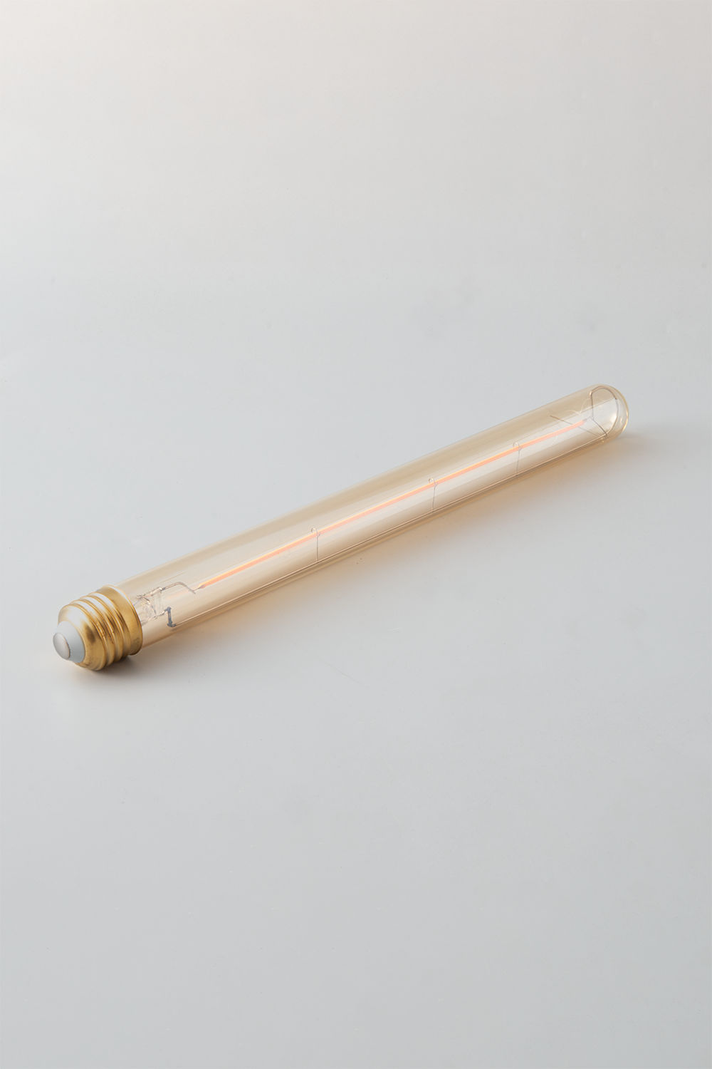 Close-up of Goldenline T8 LED bulb featuring warm amber glass and vintage-style filament for RH Edison Grand Sconce on a light grey background