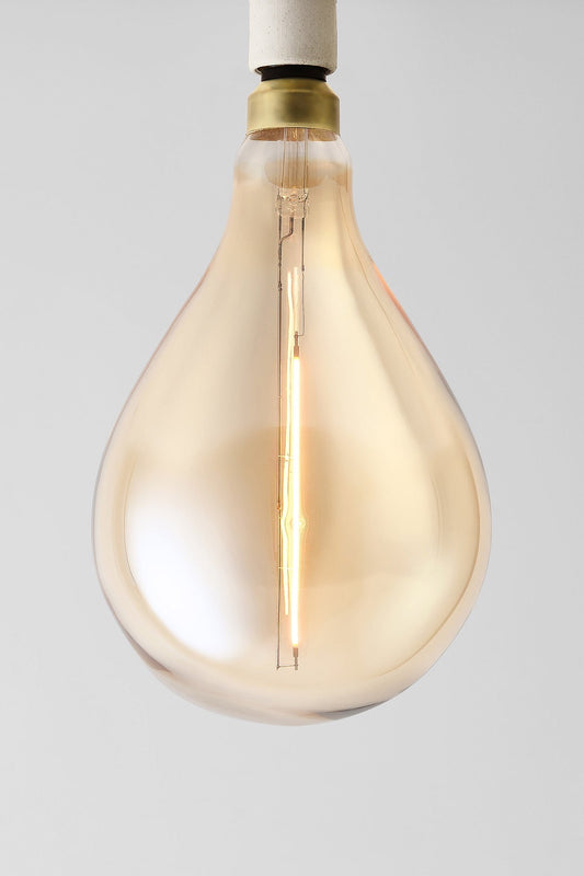 Modern teardrop LED light bulb with warm vintage Edison style glow
